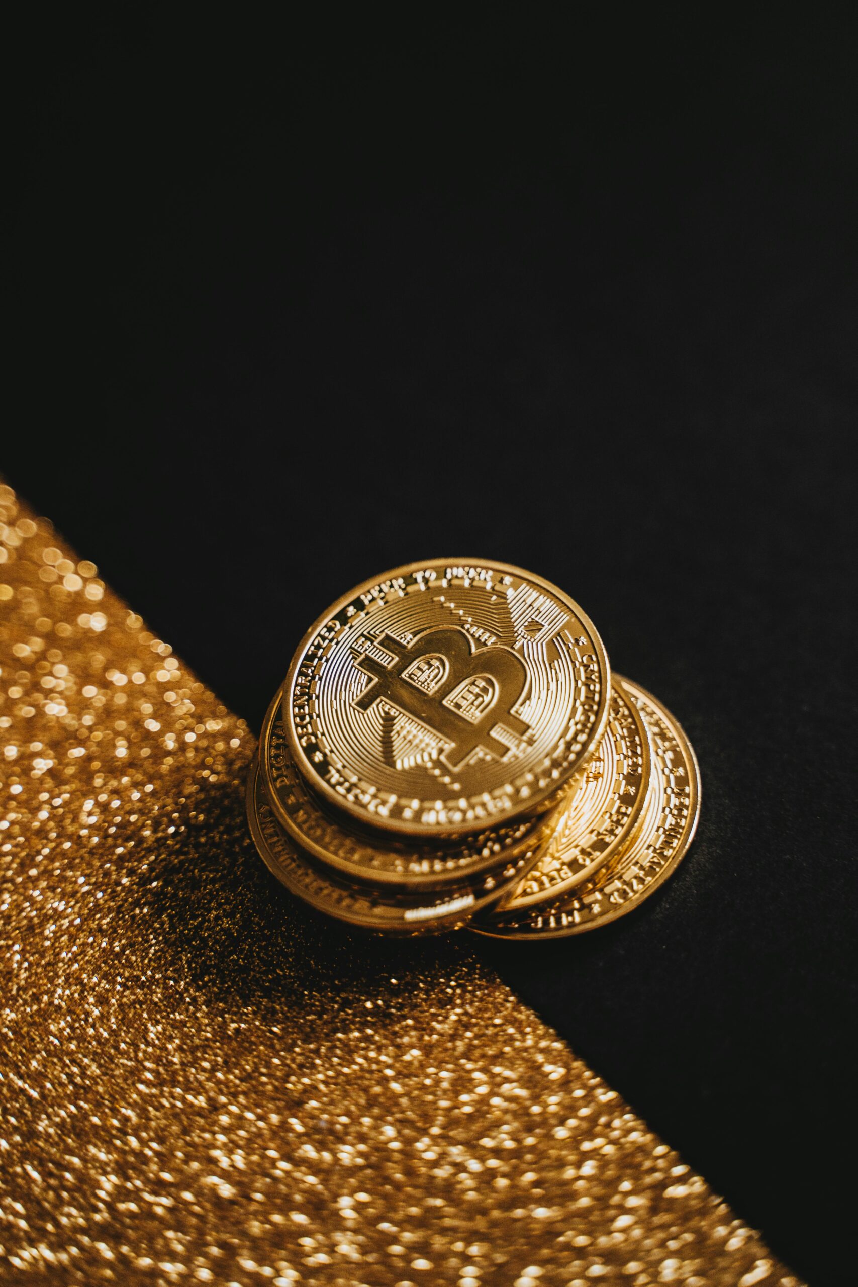 Close-up of bitcoin coins on a gold glitter background, symbolizing wealth and investment.